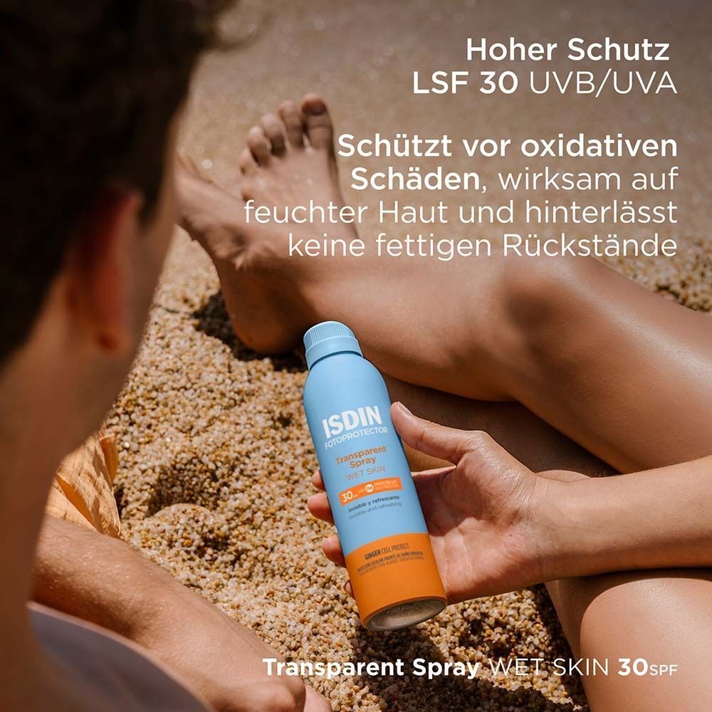 Person hält eine blaue Sprühflasche. Aufschrift: ISDIN Fotoprotector Transparent Spray Wet Skin 30. Text: Hoher Schutz LSF 30 UVB/UVA.