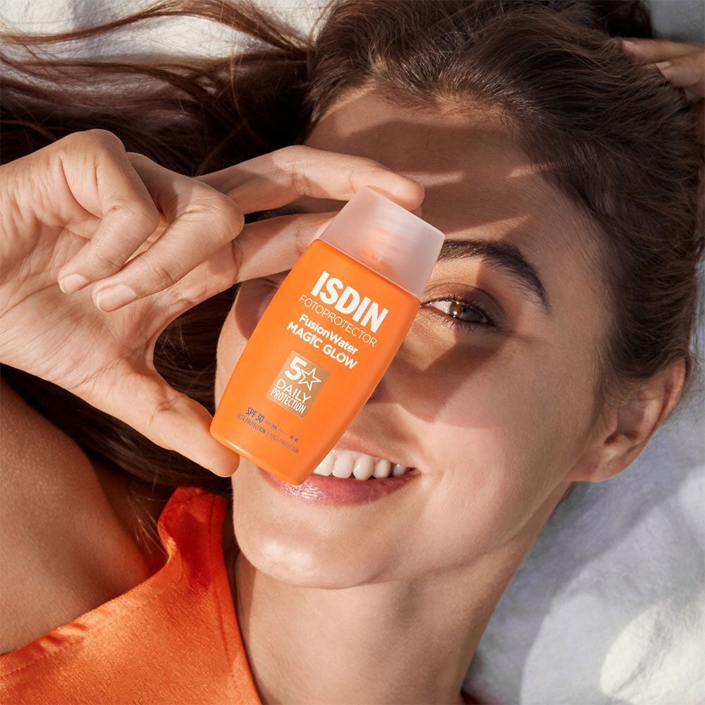 Frau hält eine orangefarbene Sonnencremeflasche vor ihr Gesicht. Auf der Flasche ist Text zu sehen.