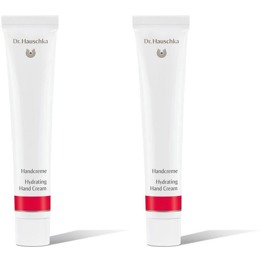 Zwei weiße Tuben Dr. Hauschka Handcreme mit rotem Band.