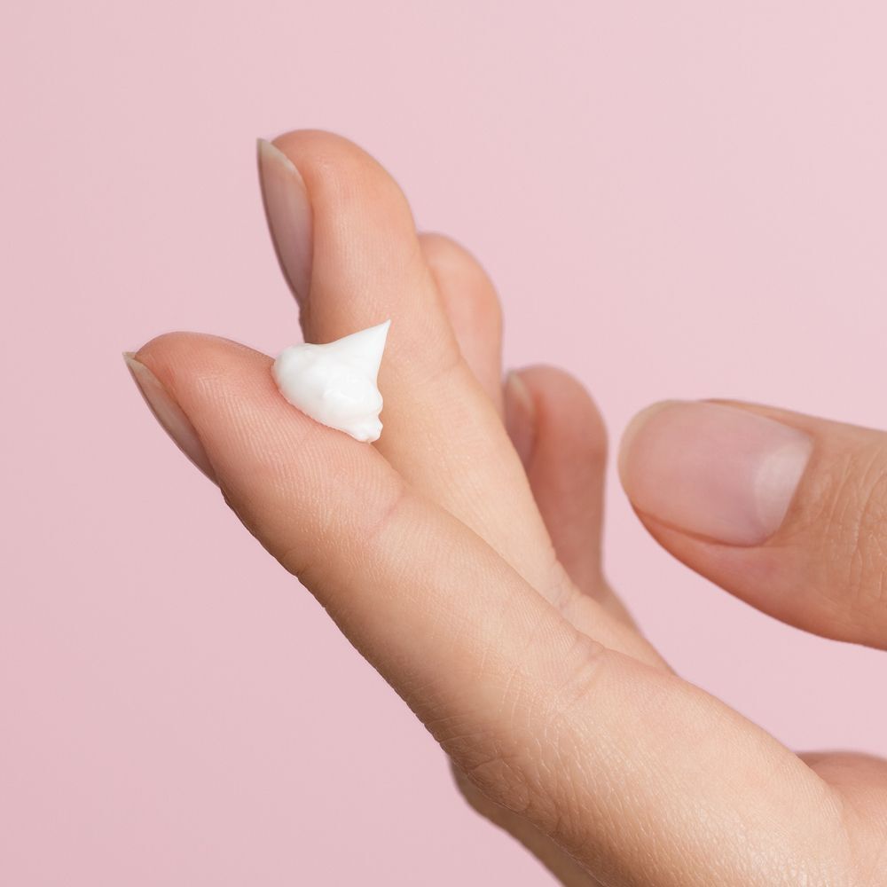 Eine kleine Menge weißer Creme auf einem Finger.