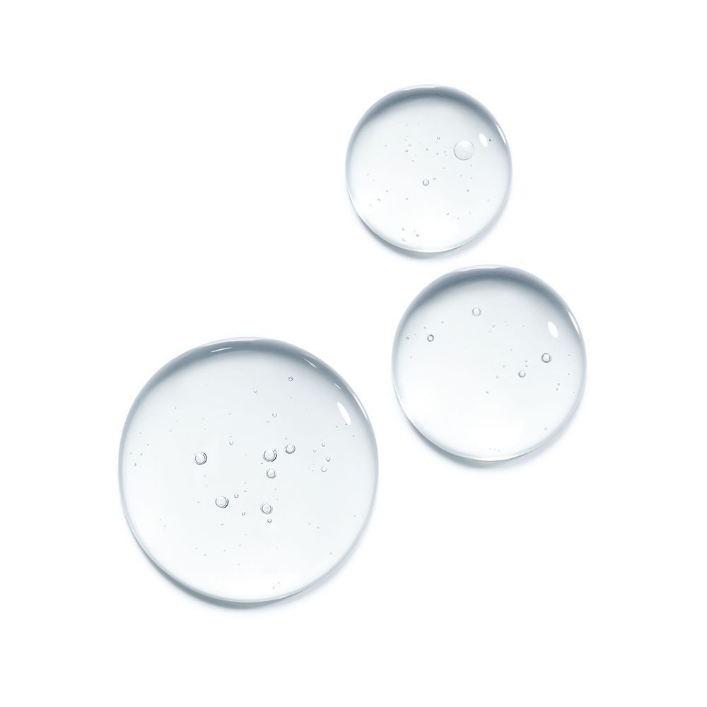 Drei transparente Serumtropfen auf weißem Hintergrund. Runde Form mit kleinen Blasen.