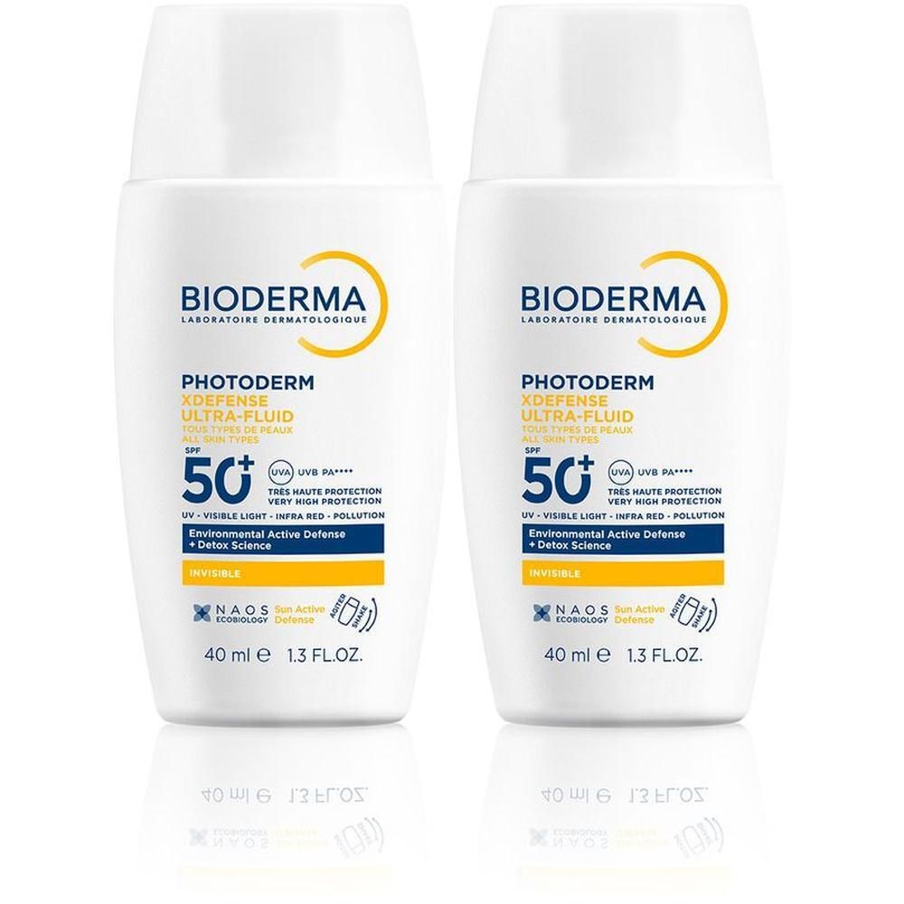 Zwei weiße Flaschen mit gelben und blauen Etiketten. Aufschrift: BIODERMA Photoderm Xdefense Ultra-Fluid LSF 50+.