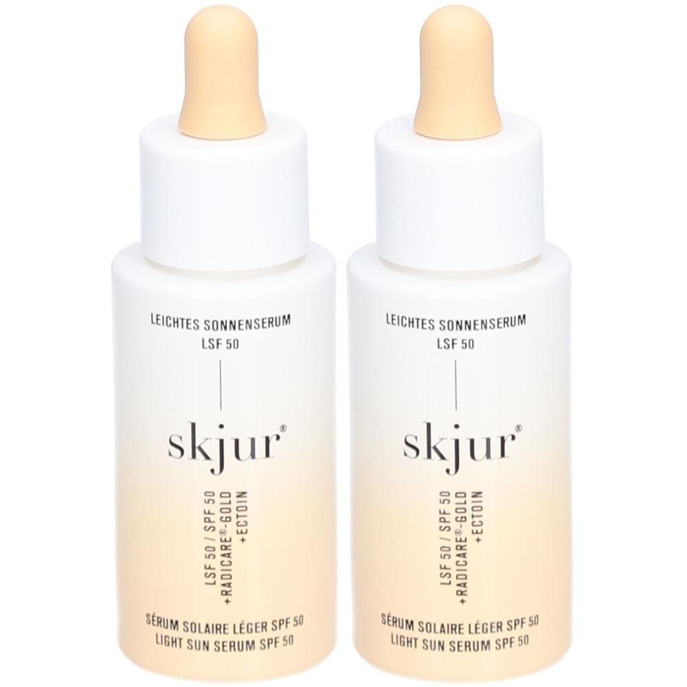 Zwei Flaschen skjur® leichtes Sonnenserum LSF 50. Weiße Flaschen mit beigefarbenem Farbverlauf. Mit Pipettenaufsatz.