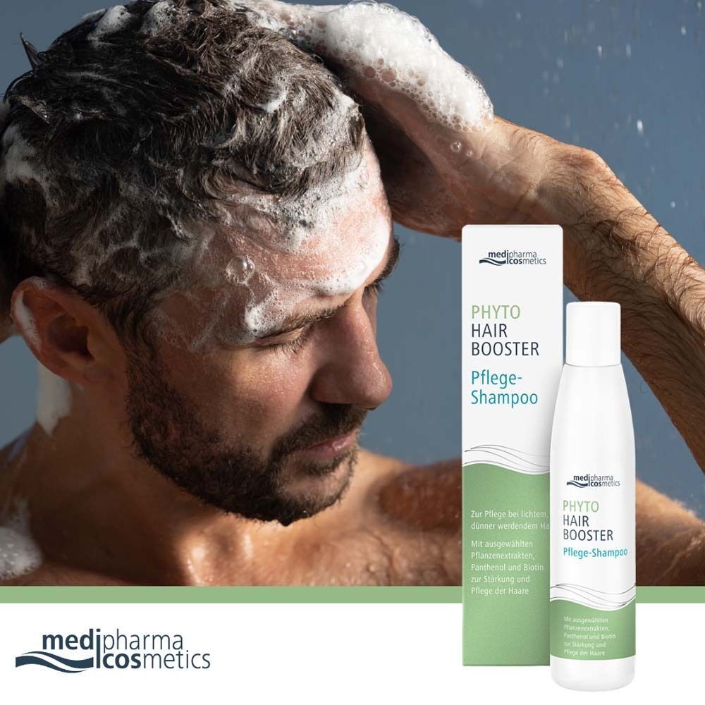 Ein Mann wäscht sich die Haare unter der Dusche. Neben ihm steht eine Flasche PHYTO HAIR Booster Pflege-Shampoo.