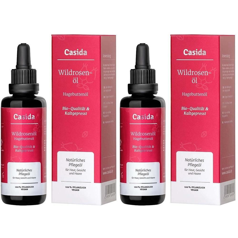 Drei Flaschen Wildrosenöl mit Verpackung. Schwarze Flaschen mit Pipette. Rote Verpackung mit Produktinformationen und Logo.