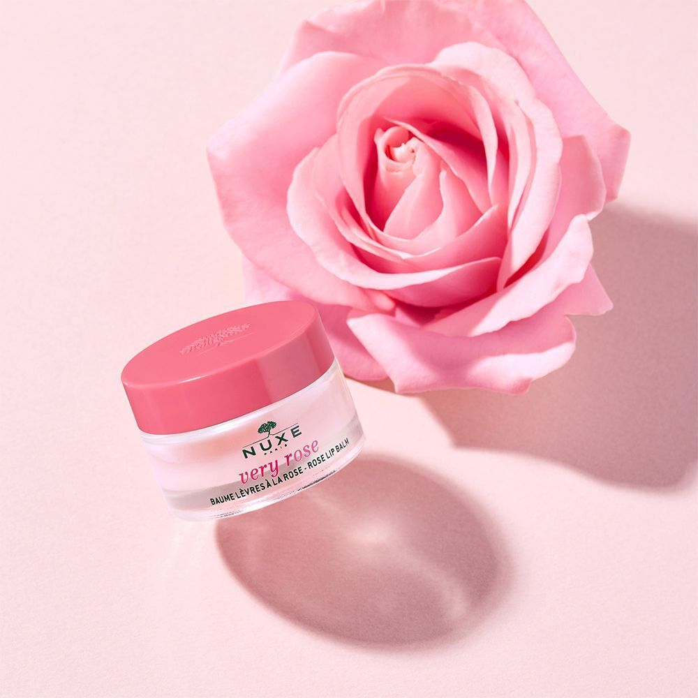 Ein rosa Lippenbalsam-Tiegel mit Rose im Hintergrund. Aufschrift: NUXE Very Rose. Text: Baume Lèvres à la Rose.