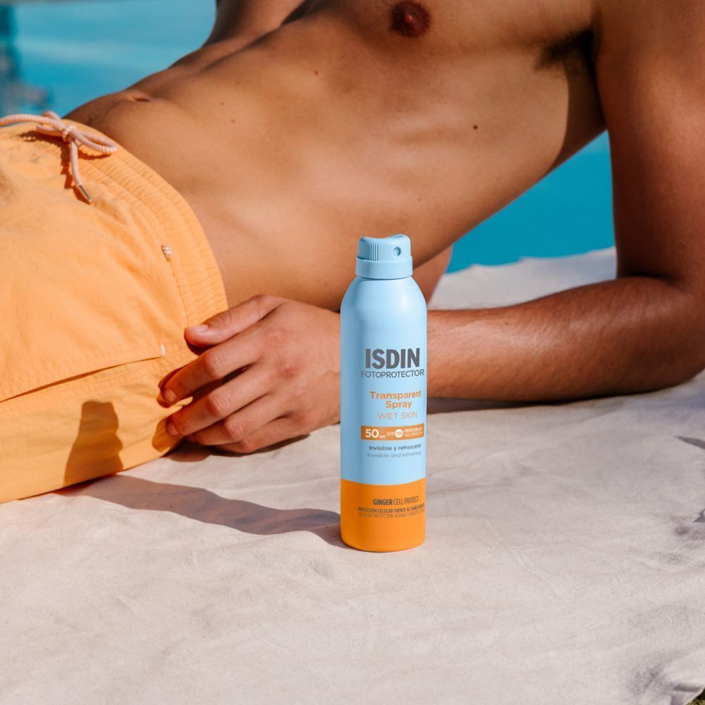 Mann liegt am Pool. ISDIN Fotoprotector Wet Skin Transpar. Spray LSF 50. Hellblaue Flasche mit orangefarbenem Boden. LSF 50.