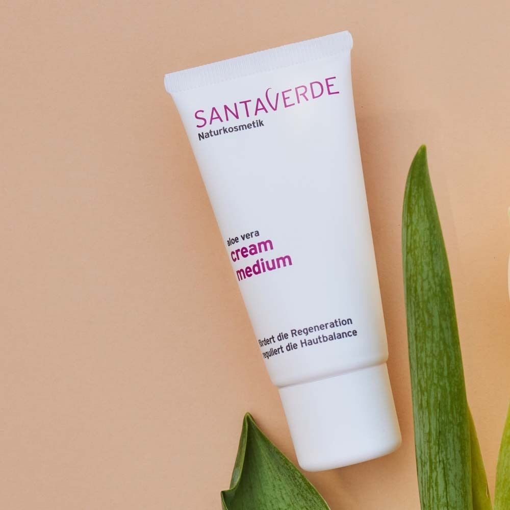 Eine Tube SANTAVERDE Creme medium. Weiße Tube mit lila Schriftzug. Aufschrift: FACE CARE cream medium. Regenerationsfördernd und ausgleichend.