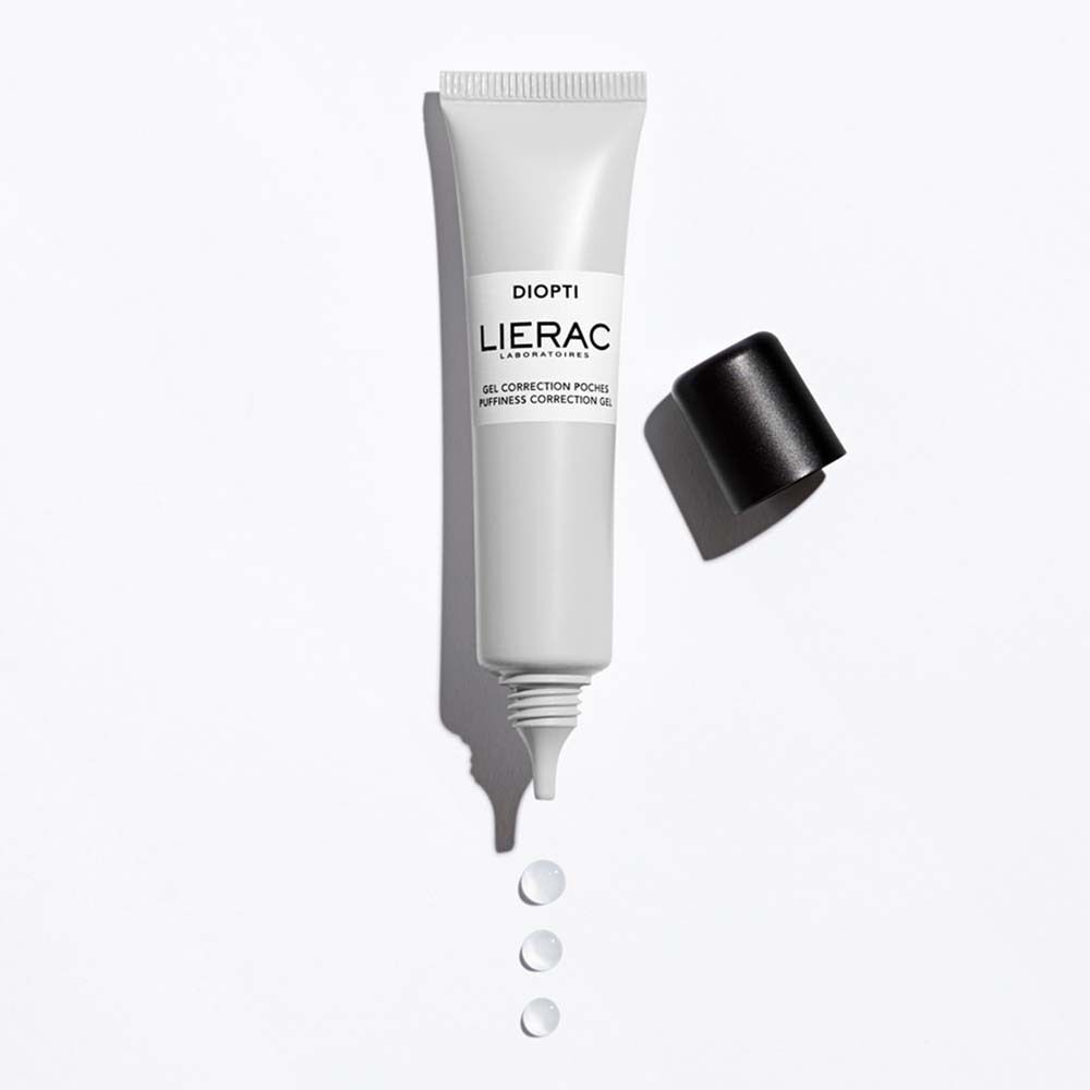 Eine Tube Augengel, weiß mit schwarzem Deckel. Aufschrift: DIOPTI, LIERAC, GEL CORRECTION POCHES, PUFFINESS CORRECTION GEL. Drei Tropfen Gel.
