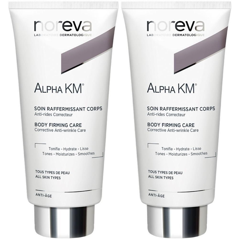Zwei Tuben noreva Alpha KM Körpermilch. Weiß, mit grauen Akzenten. Aufschrift: Alpha KM, Body Firming Care, Anti-Age. Für alle Hauttypen.