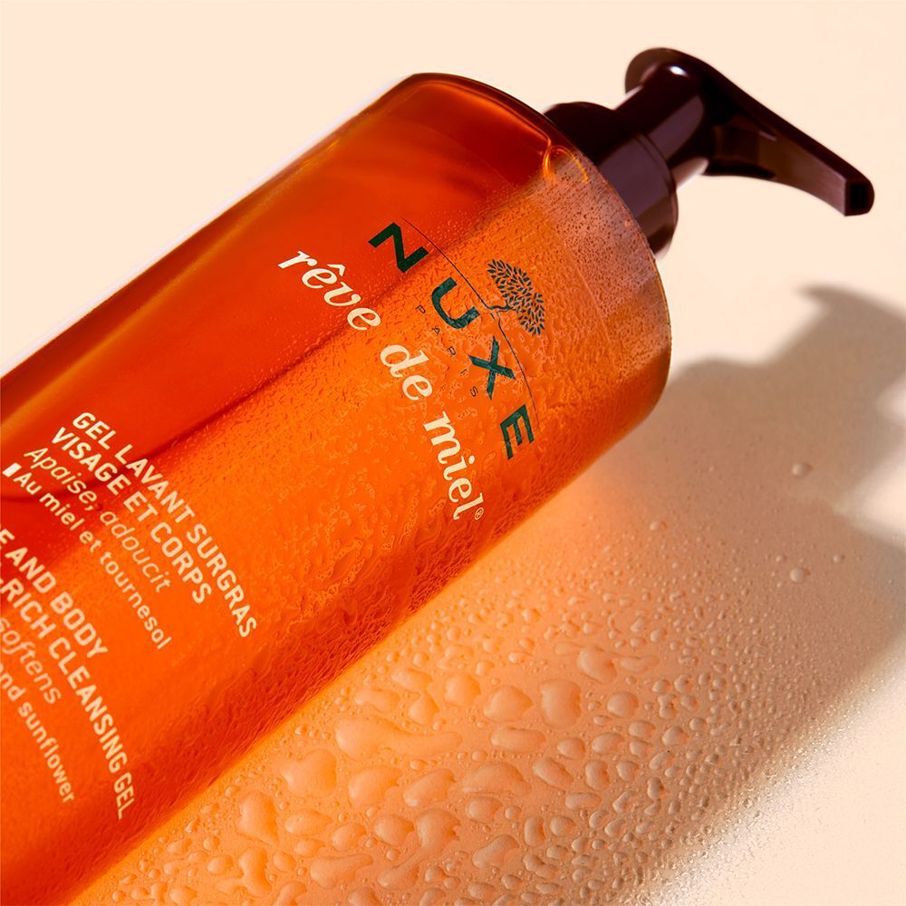 NUXE Rêve de Miel® Duschgel, orangefarbene Flasche mit braunem Pumpaufsatz. Wassertropfen auf der Oberfläche.