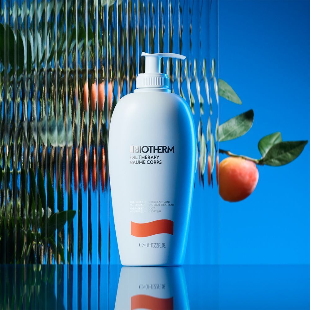 Weiße Flasche mit Pumpverschluss. Aufschrift: BIOTHERM, OIL THERAPY BAUME CORPS. Orangefarbener Streifen. Hintergrund mit Blättern und Frucht.