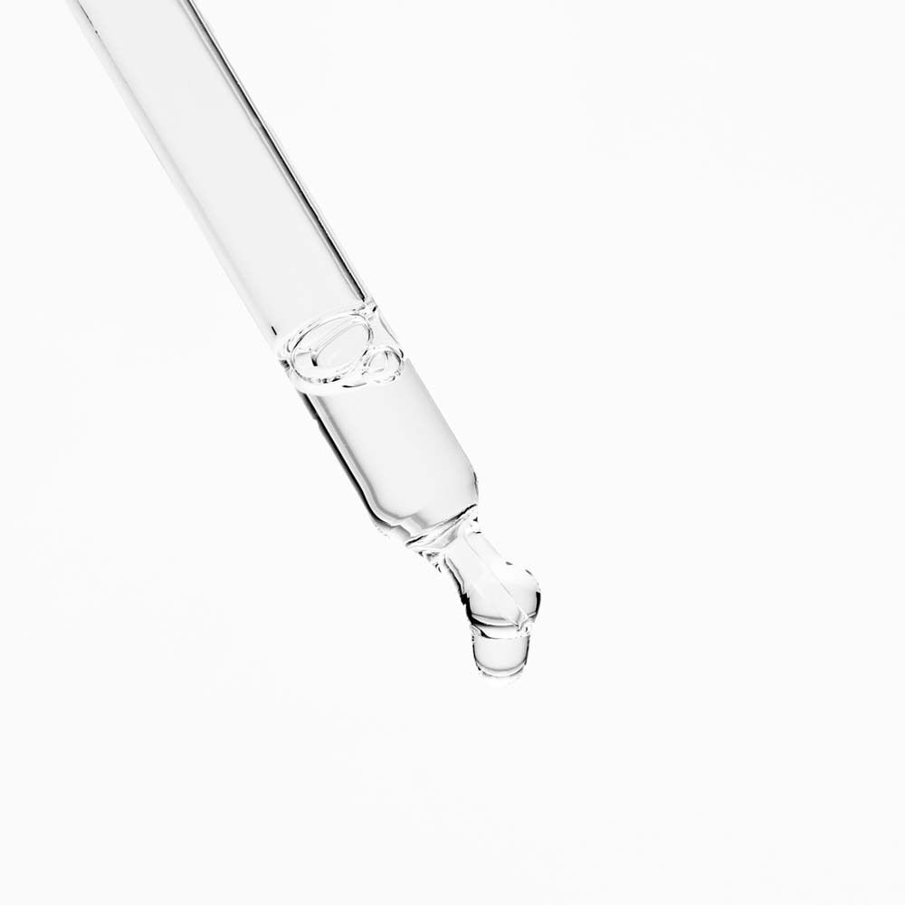 Nahaufnahme einer transparenten Pipette. Flüssigkeit tropft aus der Spitze. Weißer Hintergrund.
