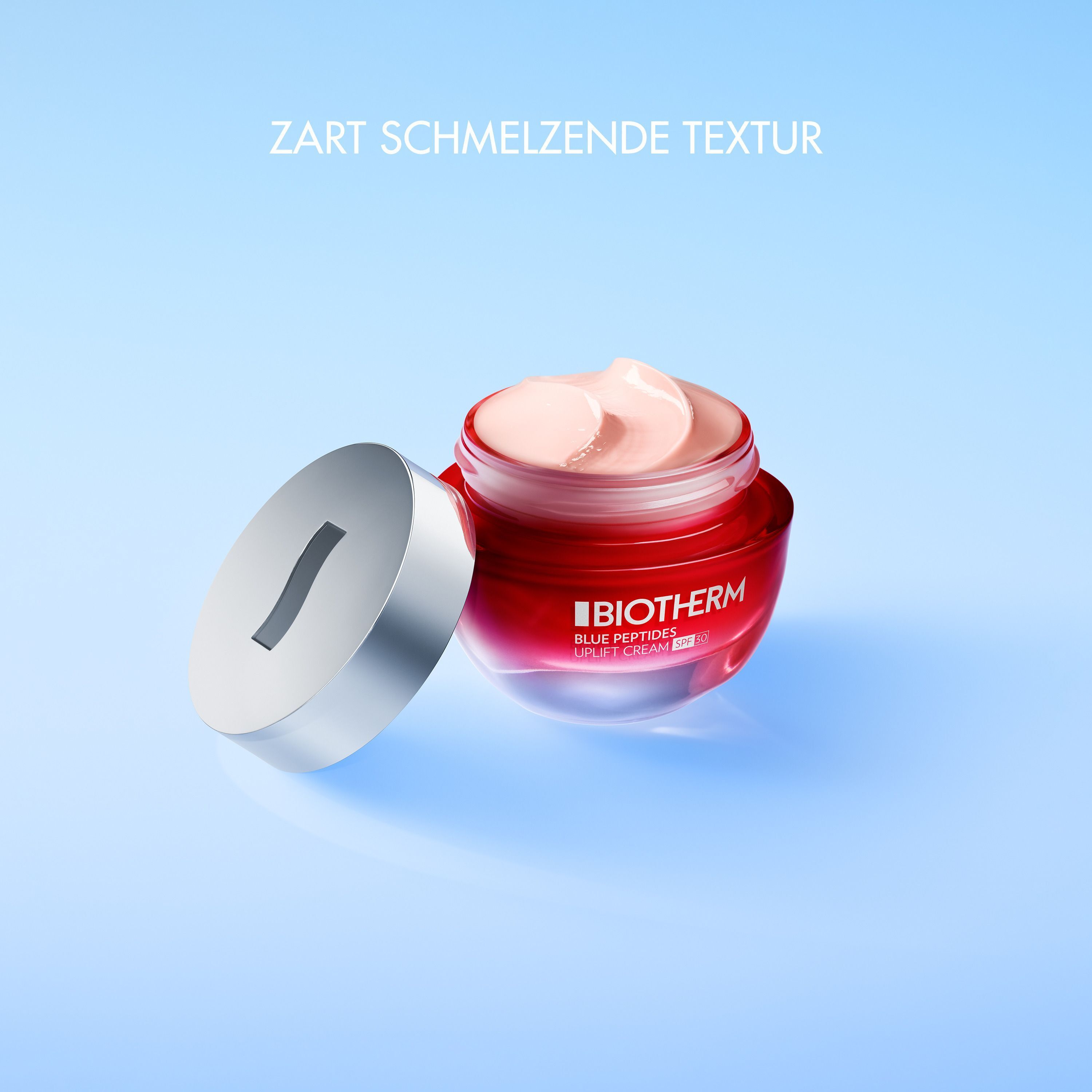 Offener Tiegel Biotherm Blue Peptides Uplift Cream SPF30. Roter Tiegel mit silbernem Deckel. Aufschrift: BIOTHERM, Blue Peptides, Uplift Cream SPF30. Text: Zart schmelzende Textur.