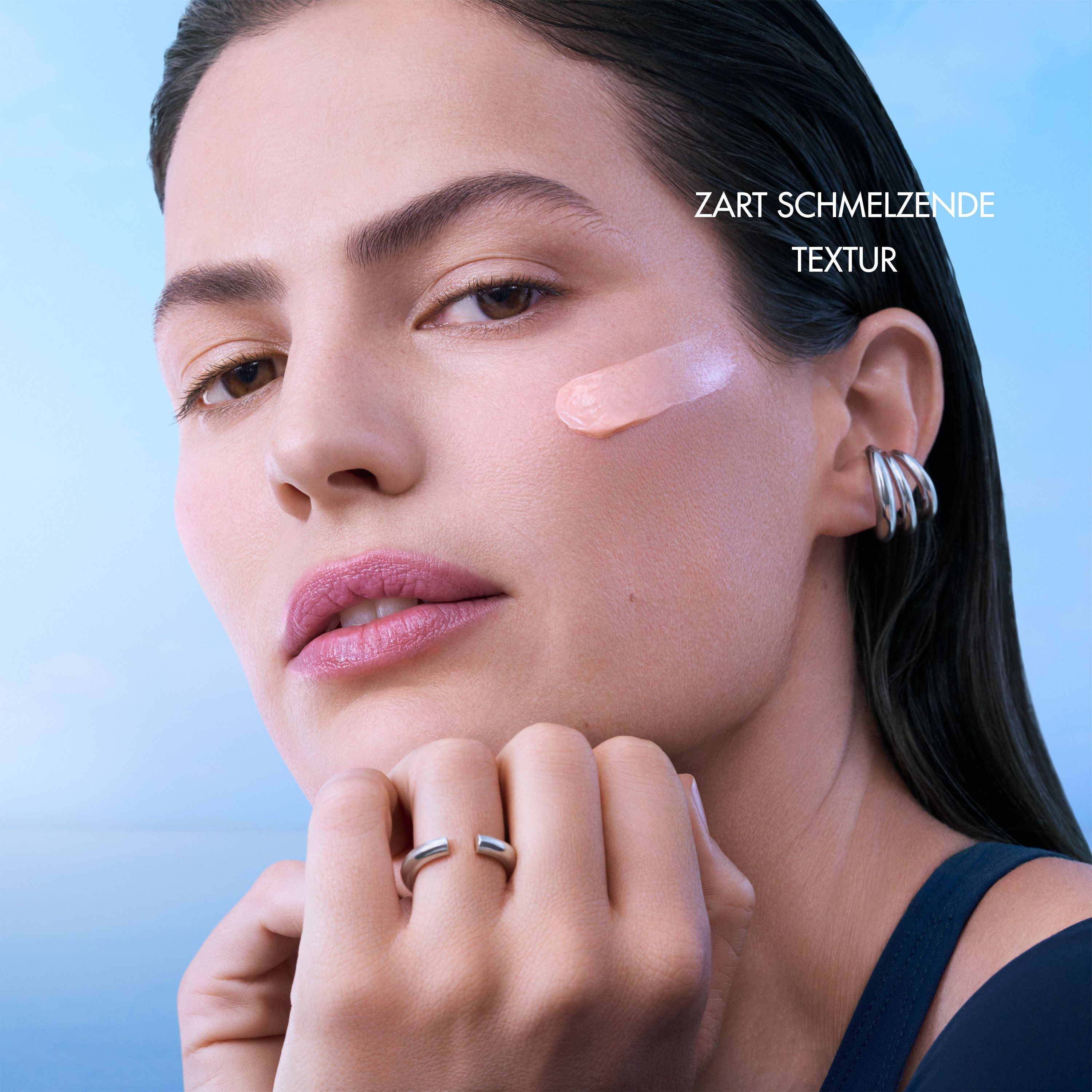 Frau mit Creme auf der Wange. Text: Zart schmelzende Textur.