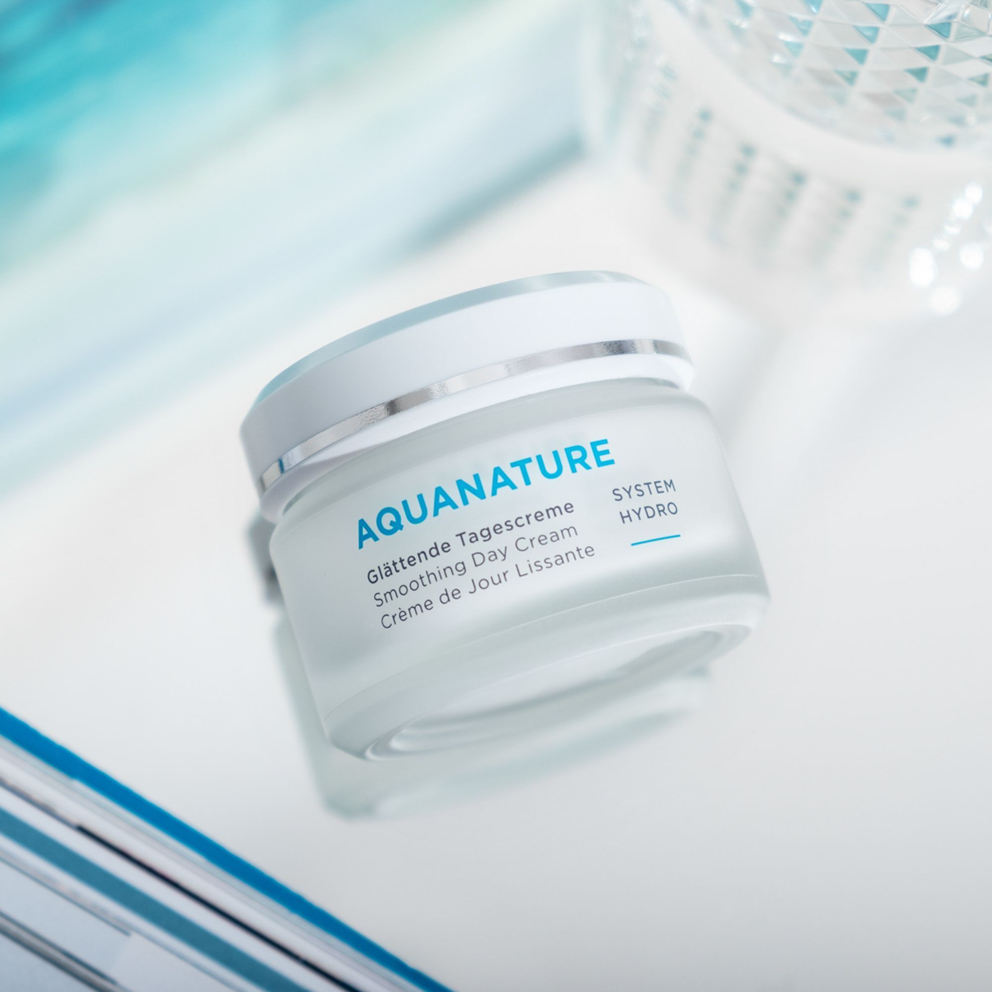 Tiegel ANNEMARIE BÖRLIND AQUANATURE Glättende Tagescreme auf reflektierender Oberfläche.