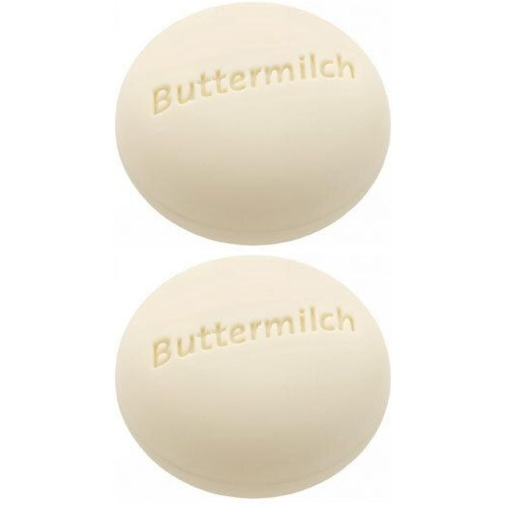 Zwei runde, cremefarbene Seifenstücke mit der Prägung "Buttermilch".