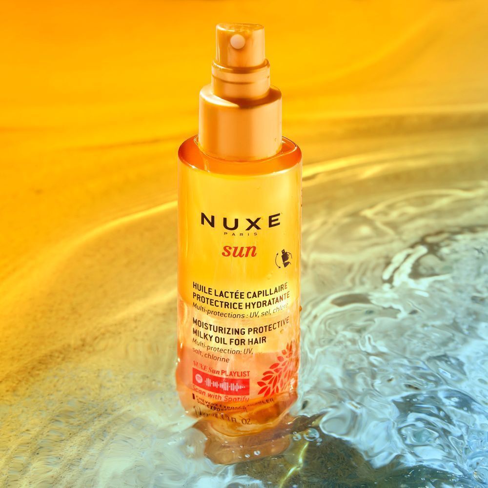 NUXE Sun Haaröl-Flasche im Wasser. Produktinformationen. Aufschrift: UV-Schutz, feuchtigkeitsspendend.