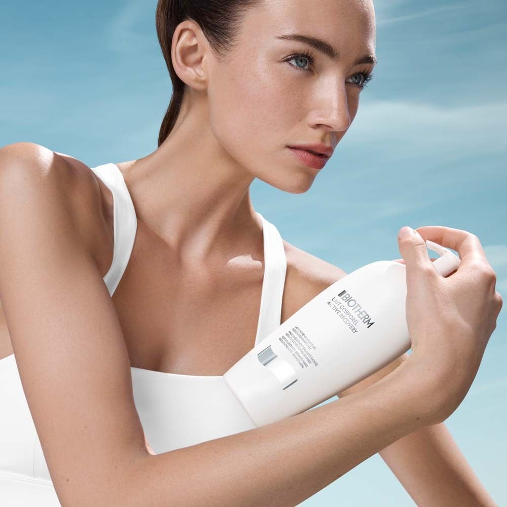 Frau hält eine weiße Flasche Biotherm Lait Corporel Active Recovery Bodylotion.