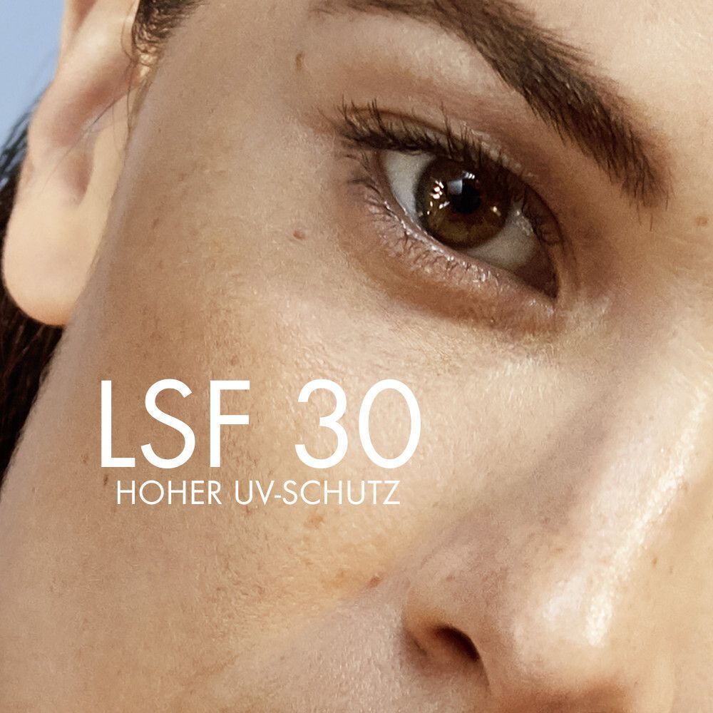 Nahaufnahme eines Gesichts. Auf der Haut steht LSF 30 und Hoher UV-Schutz. Das Gesicht ist von einem Auge bis zur Wange zu sehen.