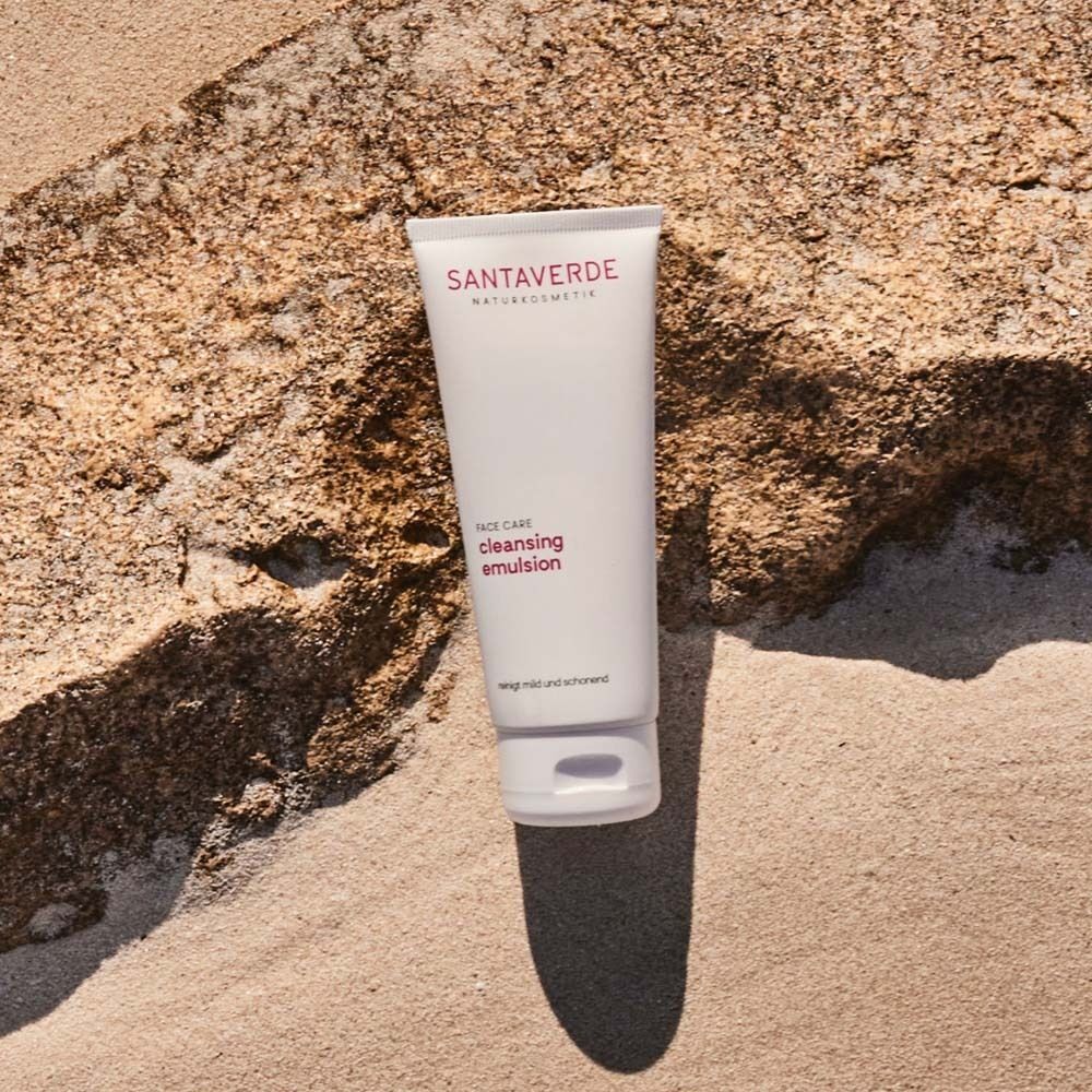 Weiße Tube SANTAVERDE auf Stein. Aufschrift: Face Care, cleansing emulsion. Text: Reinigt mild und schonend.