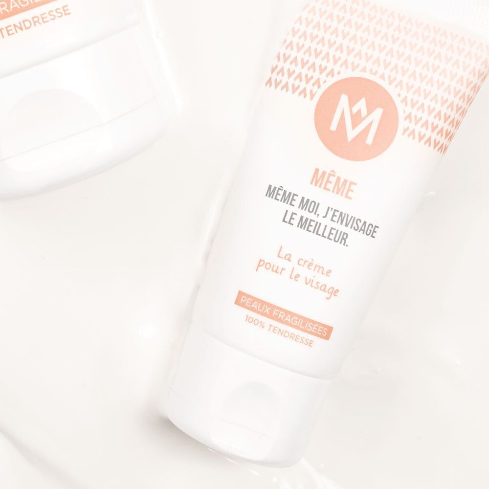 Nahaufnahme einer Tube MÊME Gesichtscreme. Weiß, mit Logo und Text. Aufschrift: MÊME, MÊME MOI, J'ENVISAGE LE MEILLEUR. La crème pour le visage. Peaux fragilisées.