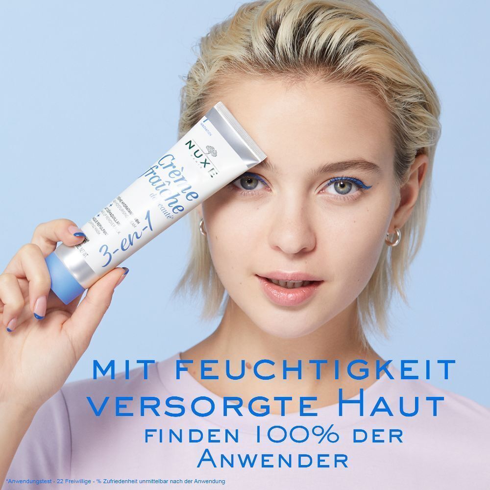Frau hält eine Tube Crème Fraîche de Beauté. Weiß, mit blauem Deckel und Schriftzug. 3-en-1 Feuchtigkeitspflege.