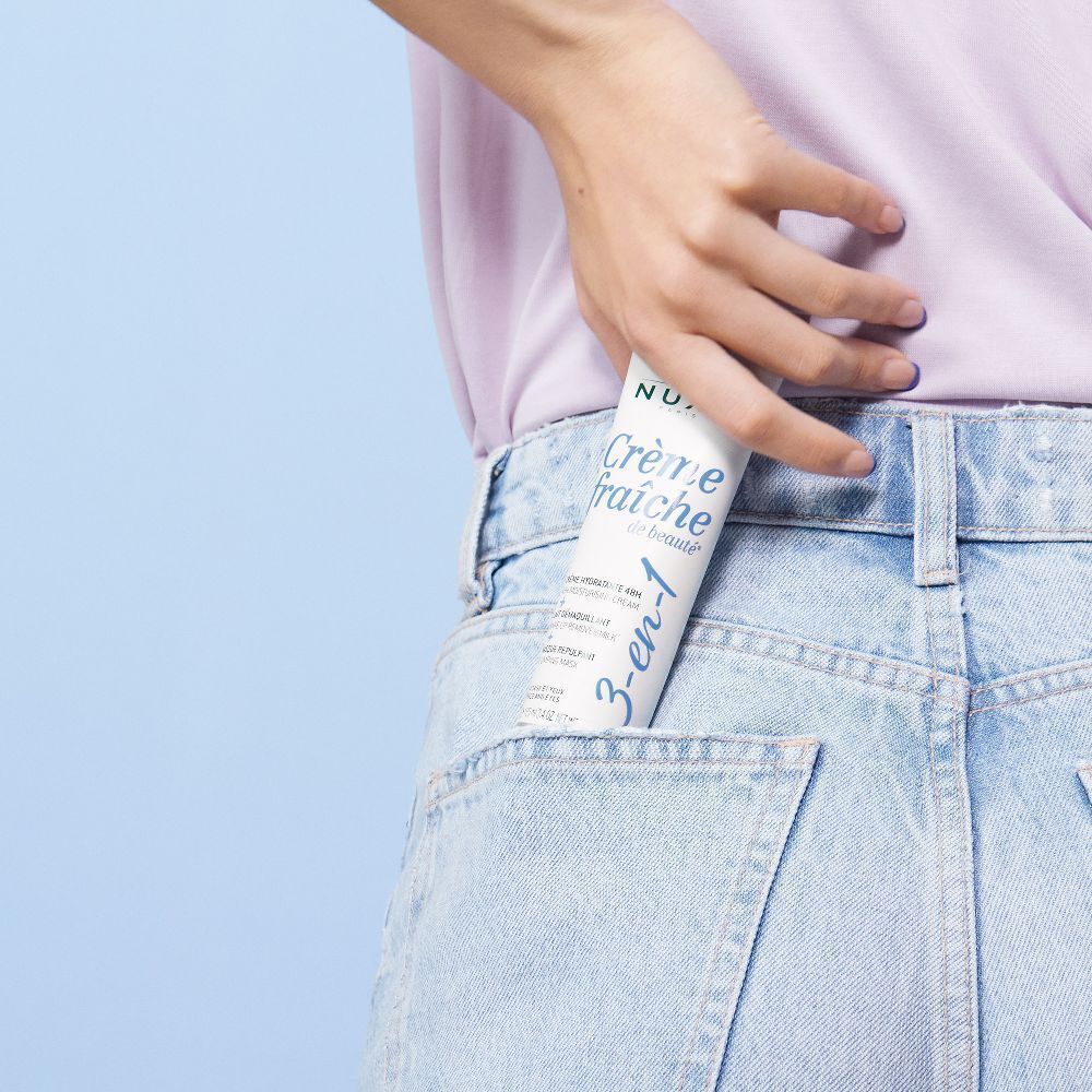 Eine Tube Crème Fraîche de Beauté in einer Jeans-Hosentasche. Weiß, mit blauem Schriftzug. 3-en-1.