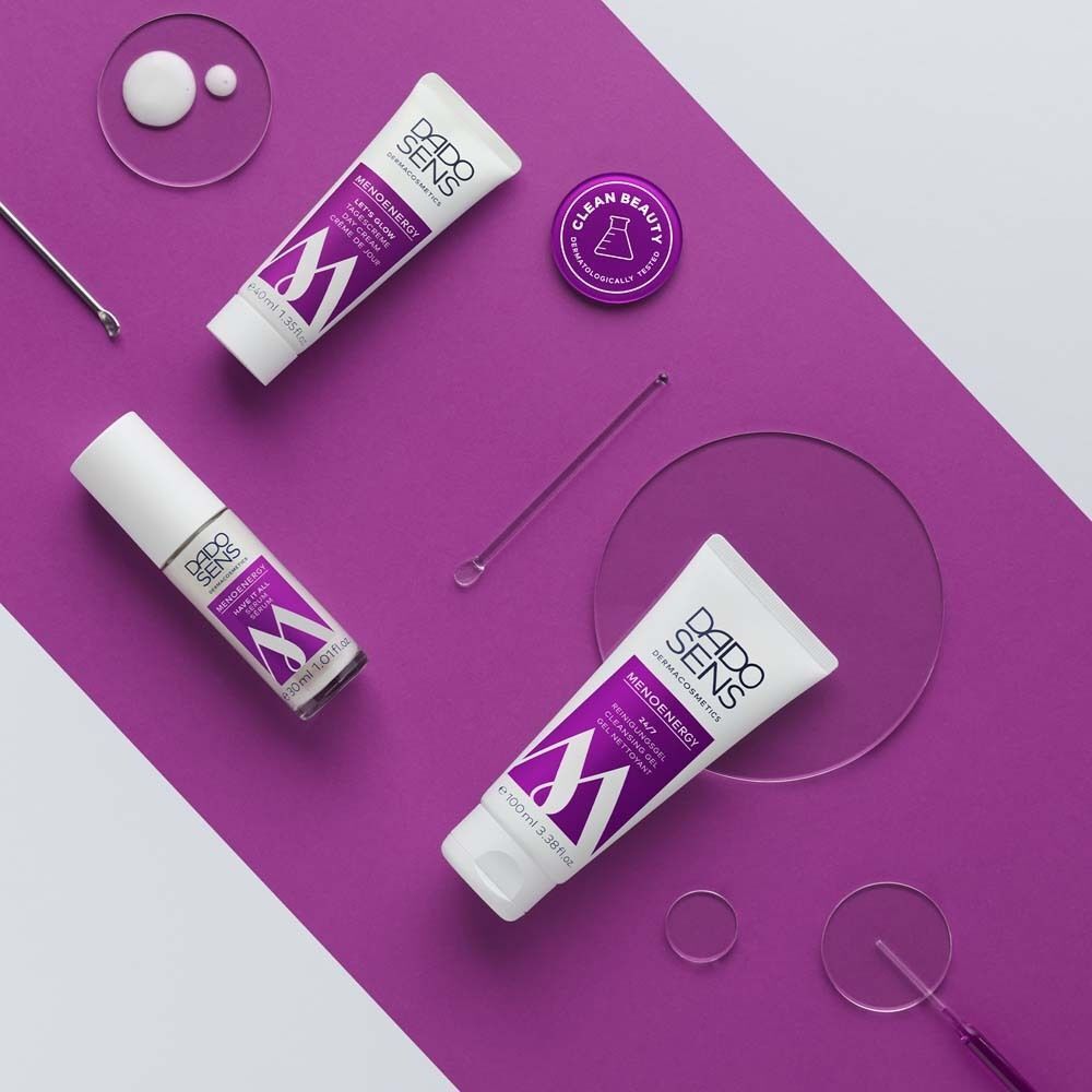 Verschiedene Produkte auf lila Untergrund. Tuben, Tiegel, und ein Serum. Marke: DADO SENS, Produkt: MENOENERGY.
