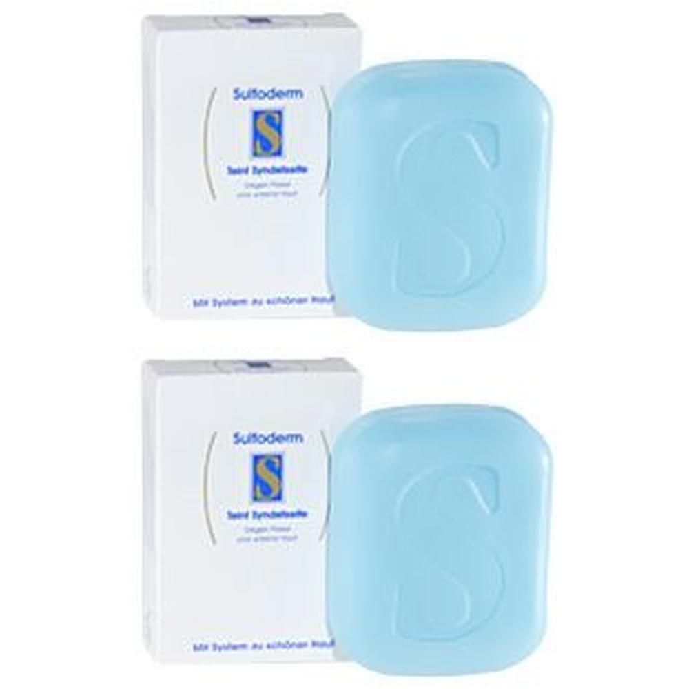Zwei Seifenstücke und Verpackungen. Blaue Seife mit großem 'S'. Verpackung mit Produktnamen und Logo.