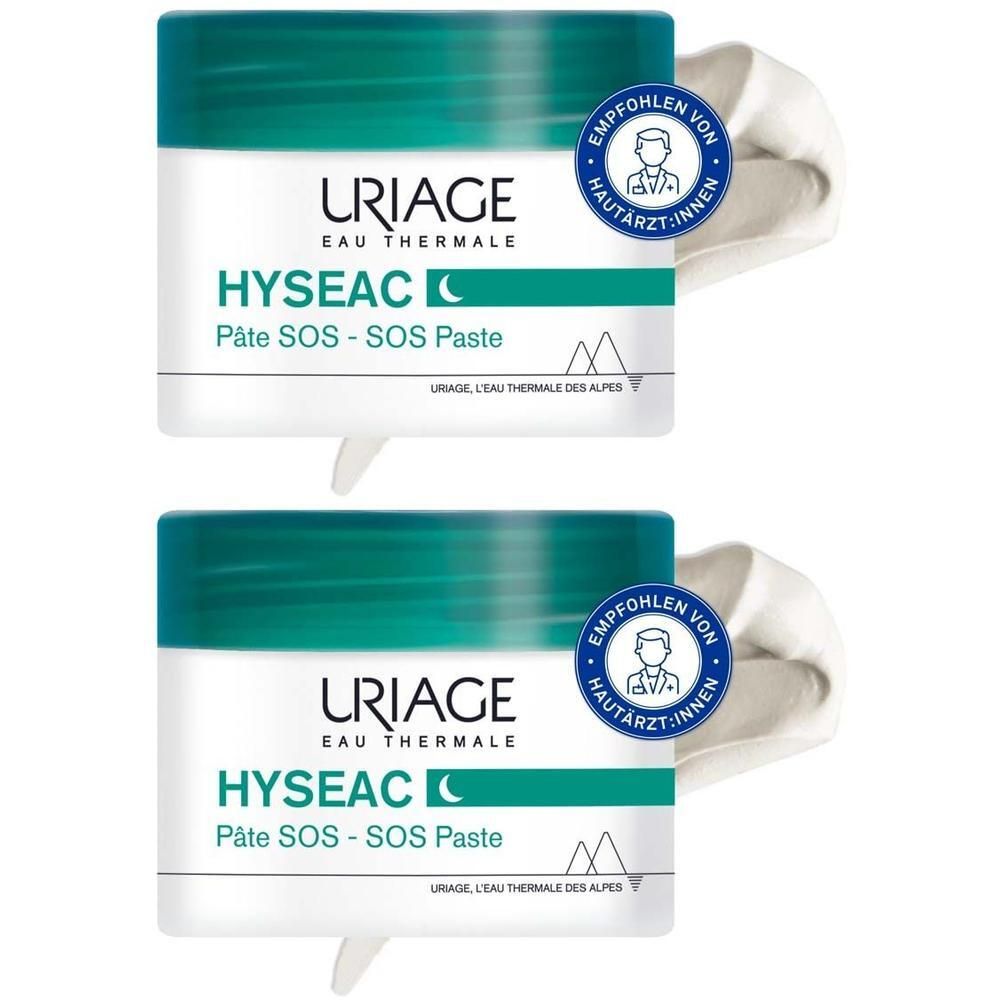 Zwei Tiegel URIAGE Hyseac SOS-Paste. Weiße Creme wird aus den Tiegeln entnommen. Aufschrift: URIAGE, Hyseac, Pâte SOS - SOS Paste.