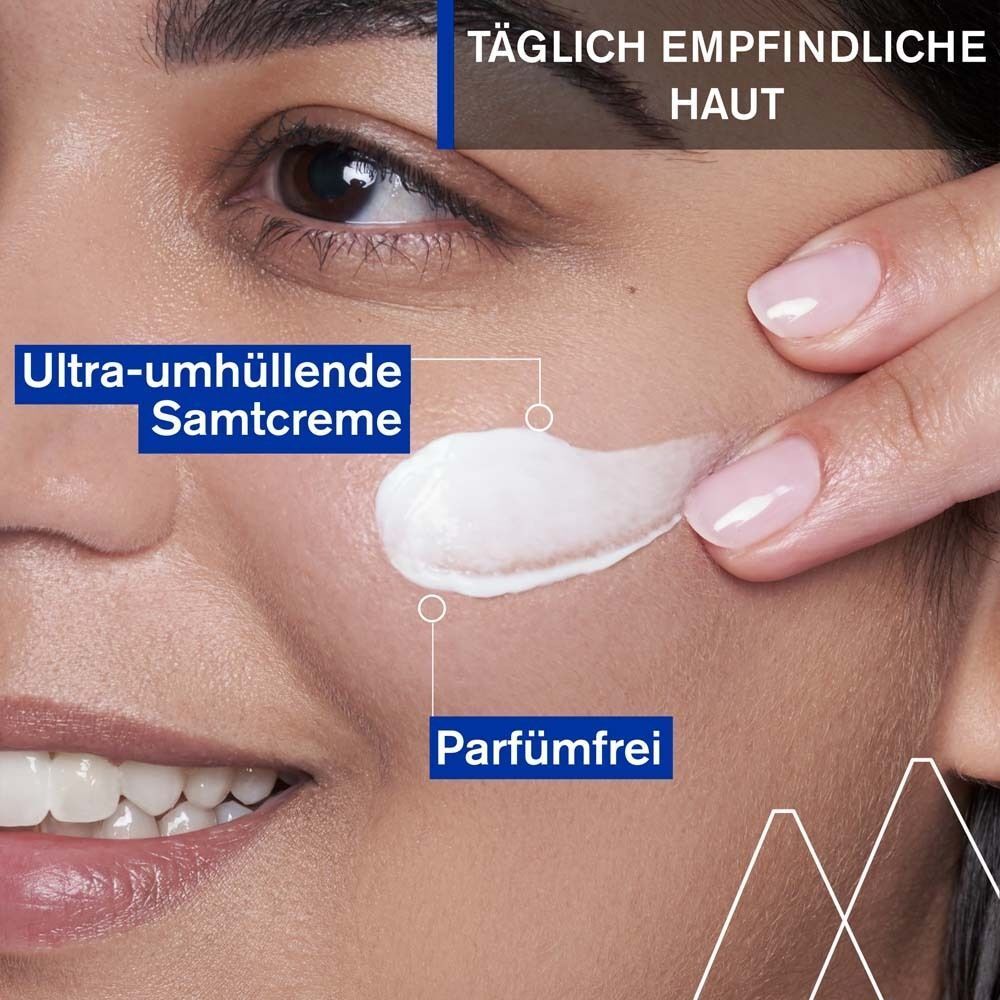 Nahaufnahme einer Frau, die Creme auf ihr Gesicht aufträgt. Text: Ultra-umhüllende Samtcreme, parfümfrei.