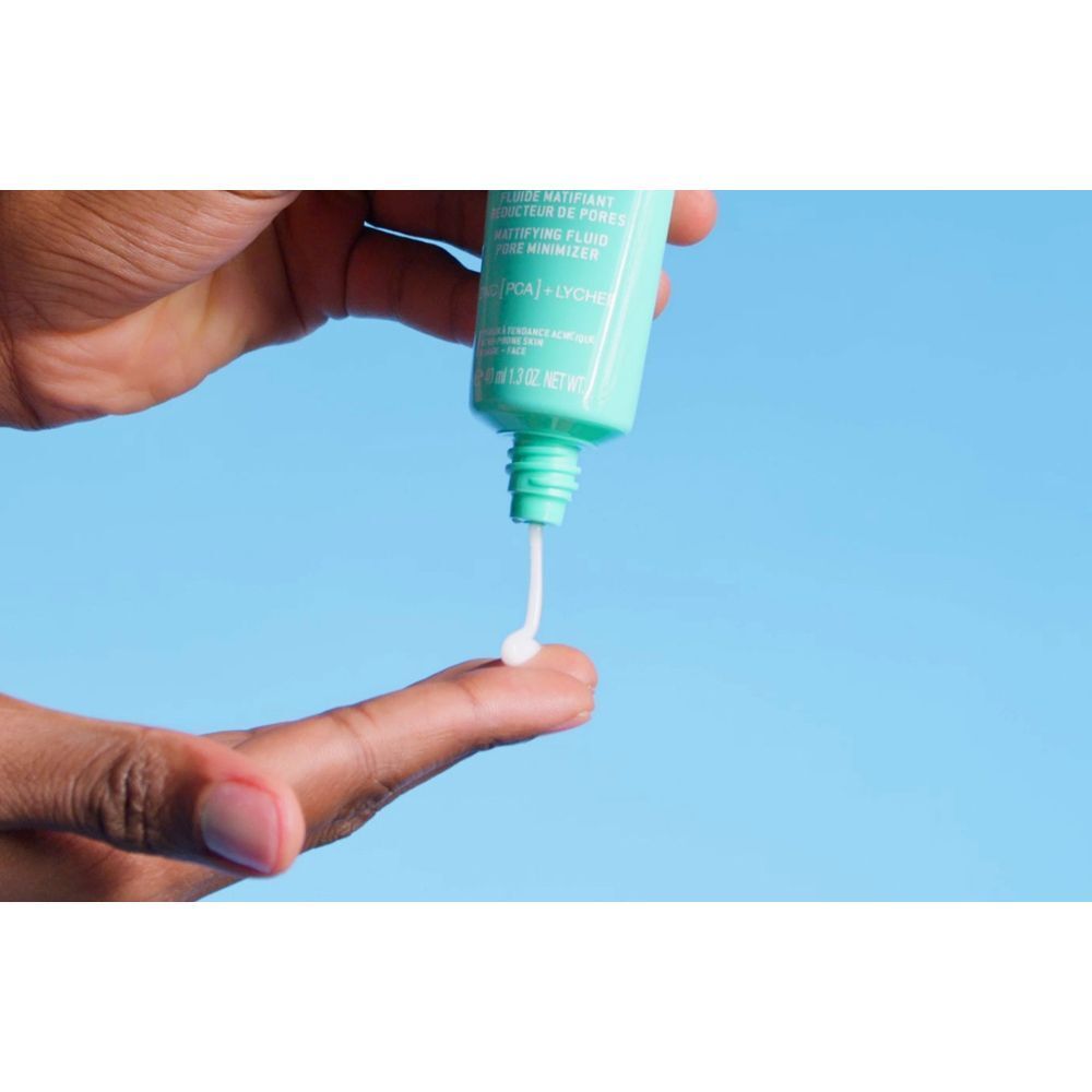 Eine Hand drückt eine kleine Menge NUXE Zinc Power Fluid aus der Tube auf einen Finger.