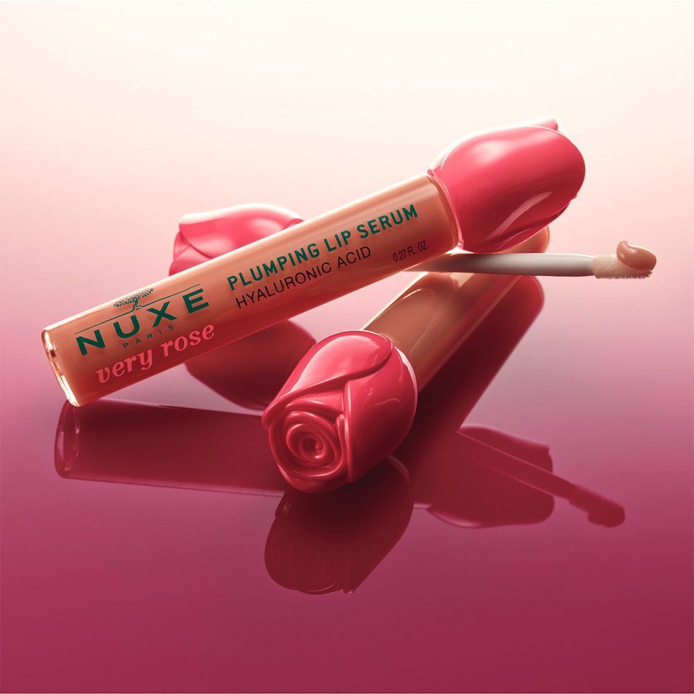 Zwei Lipgloss-Tuben mit Blütenkappen. Aufschrift: NUXE very rose, Plumping Lip Serum, Hyaluronsäure. Applikator sichtbar.