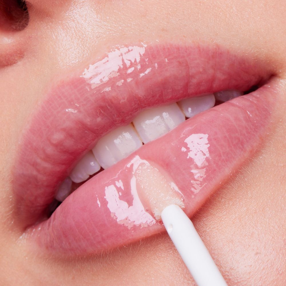 Nahaufnahme von Lippen mit Applikator. Glänzender Lipgloss.