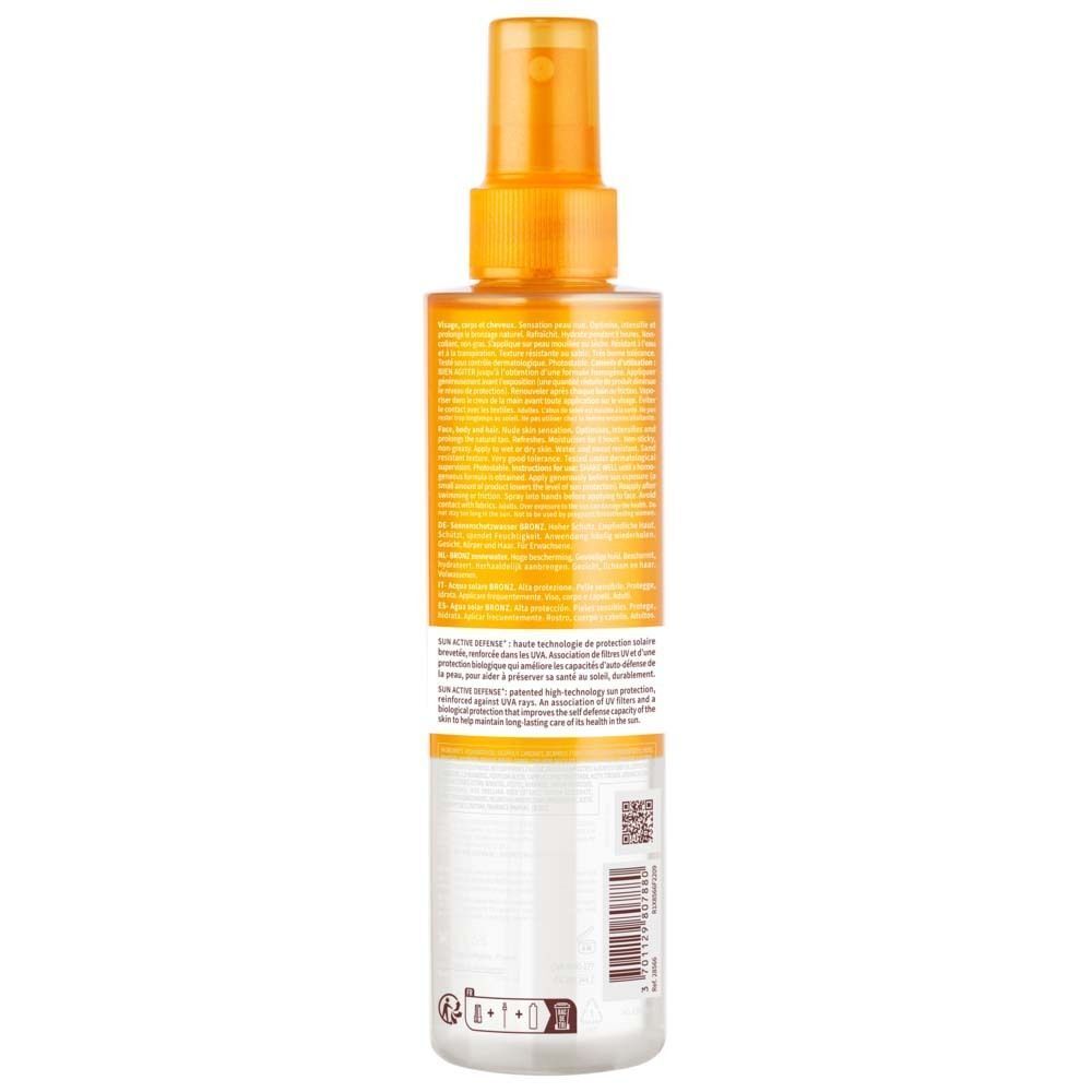 Rückseite einer BIODERMA Photoderm Eau solaire BRONZ SPF 30 Flasche. Text und Barcode. Orangefarbener Sprühkopf, transparente Flasche.