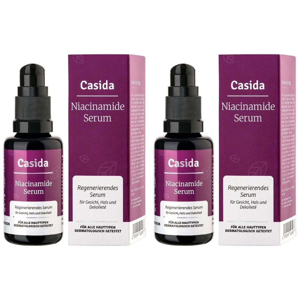 Drei Flaschen und Verpackungen des Casida Niacinamide Serums. Schwarze Flaschen mit Dosierpumpen, lila Verpackung.