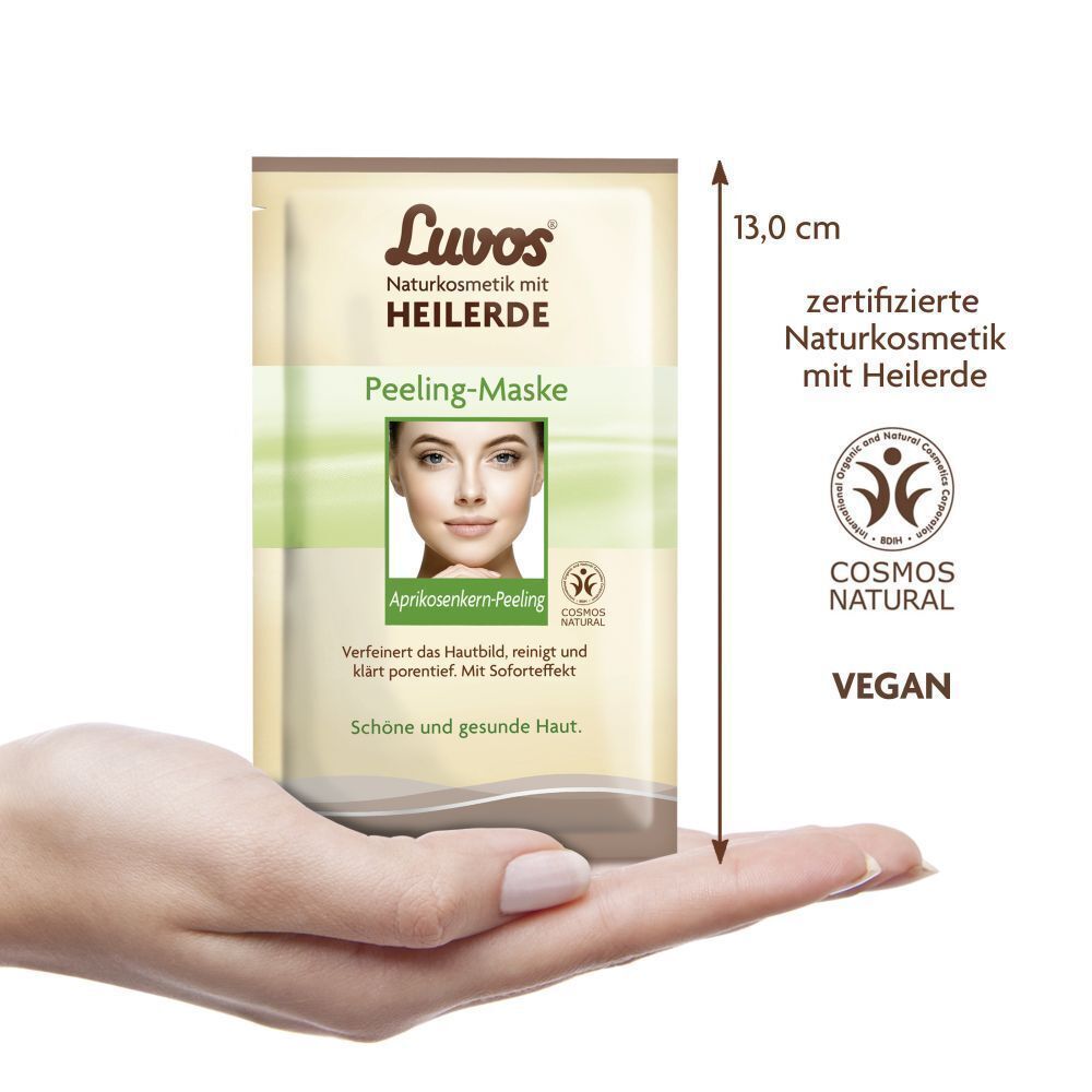 Beutel Luvos Heilerde Peeling-Maske in Hand gehalten. Abmessung 13,0 cm. Mit COSMOS NATURAL und VEGAN Siegel.
