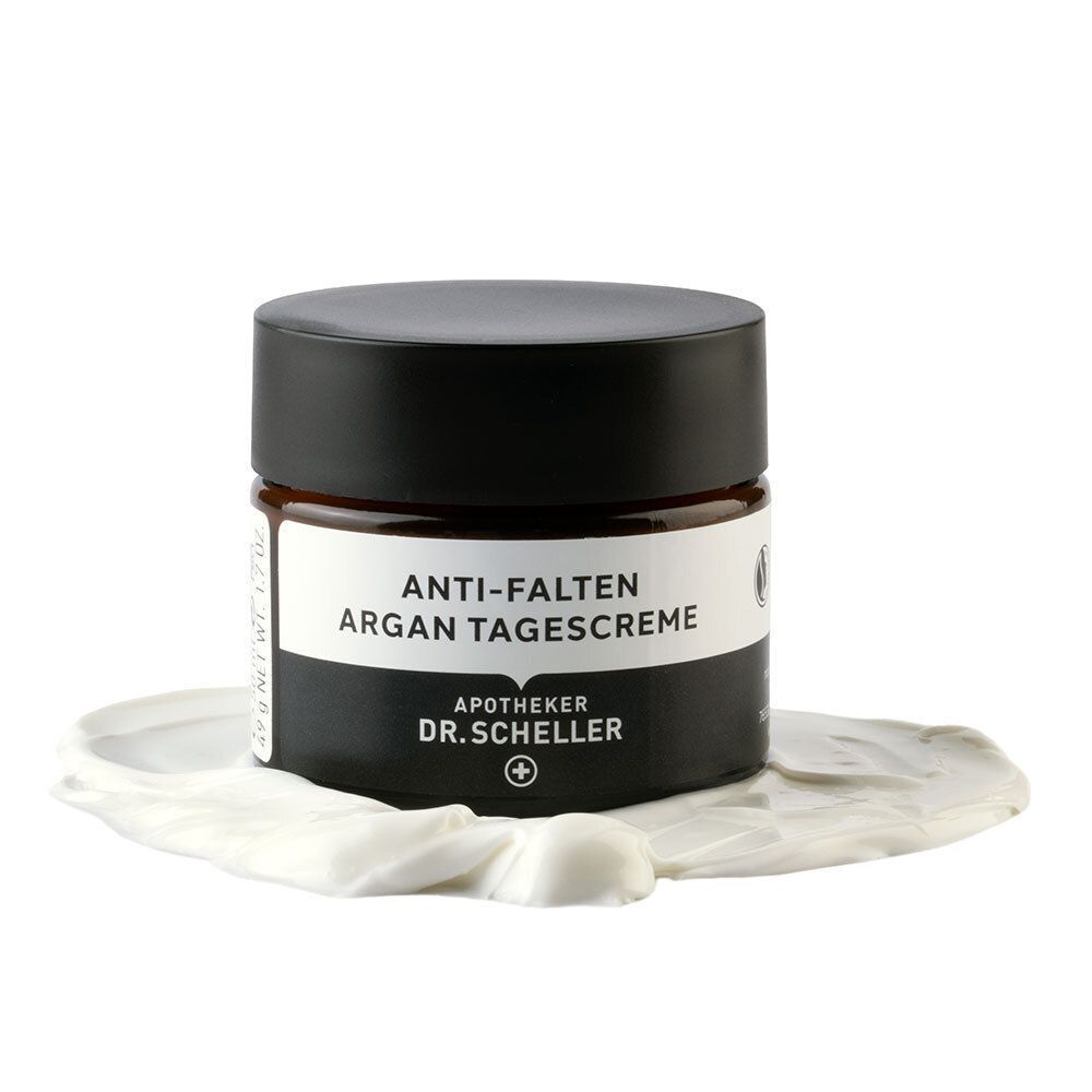 Creme-Tiegel mit schwarzem Deckel. Aufschrift: ANTI-FALTEN ARGAN TAGESCREME, DR.SCHELLER. Auf Creme-Klecks.