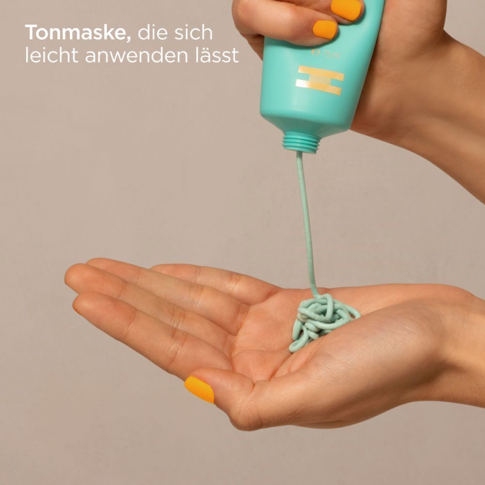 Hände halten eine Tube. Grüne Gesichtsmaske wird auf die Handfläche gedrückt. Gelbe Fingernägel.