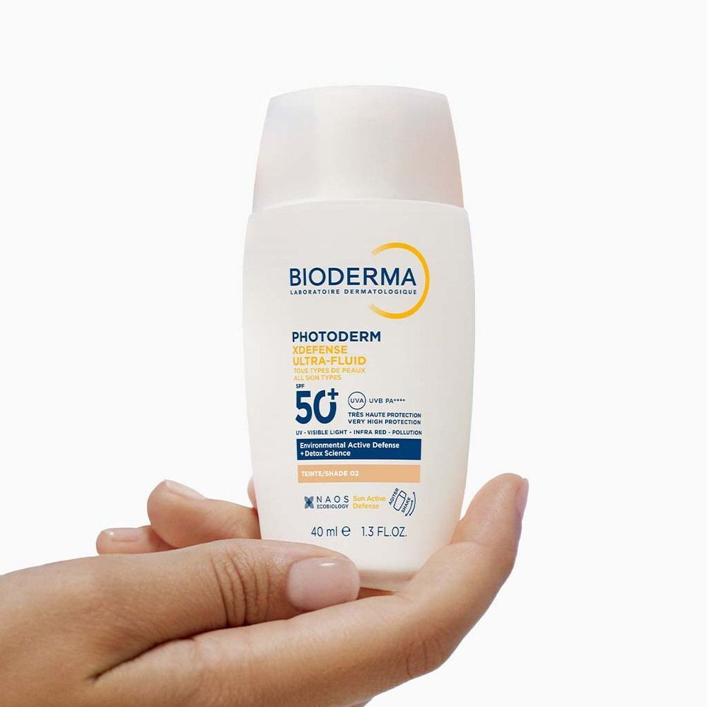 Eine Flasche in einer Hand gehalten. Aufschrift: BIODERMA, Photoderm Xdefense Ultra-Fluid, LSF 50+. 40 ml.