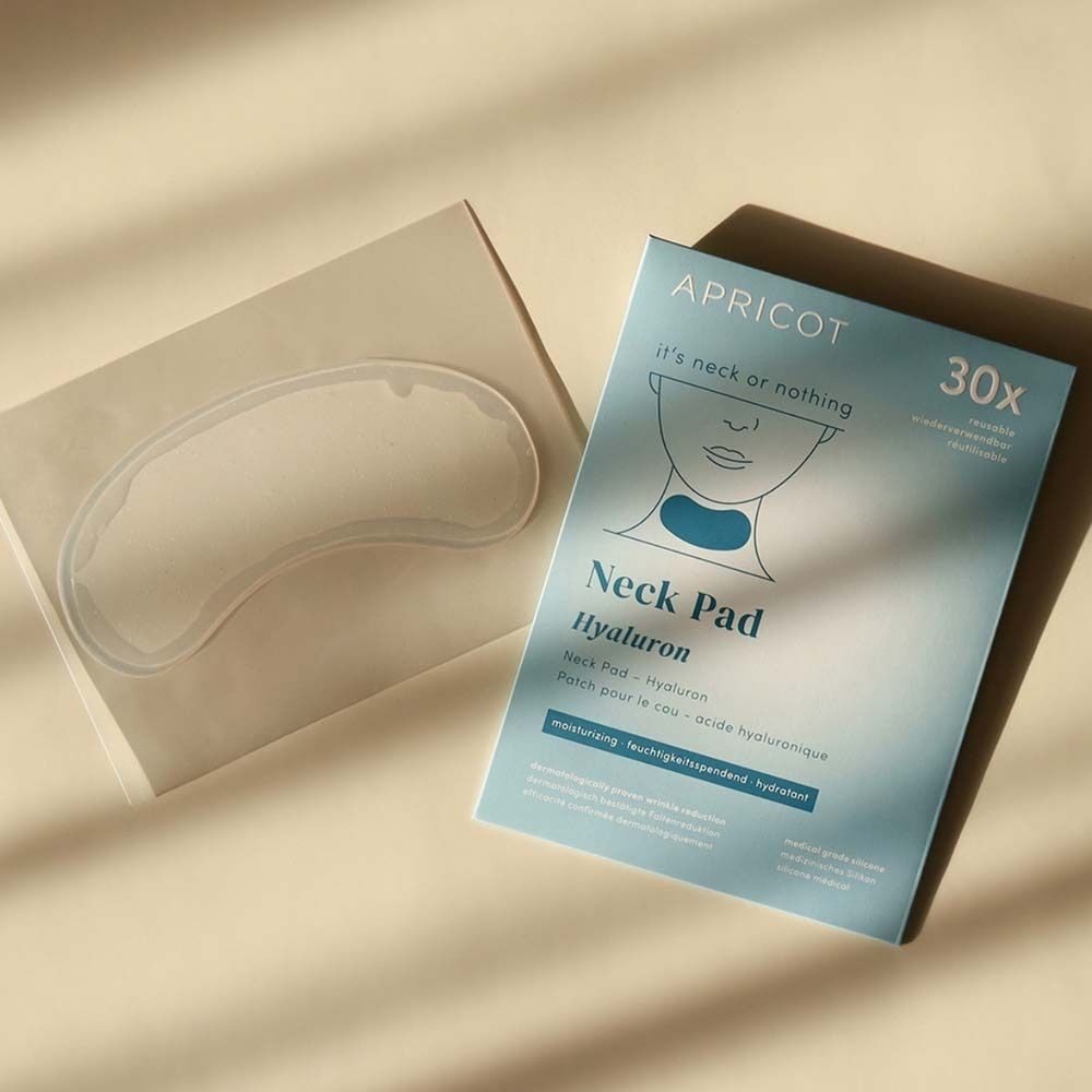 Geöffnete Verpackung mit einem Hals Pad und einer APRICOT Neck Pad Verpackung. Das Pad liegt daneben.