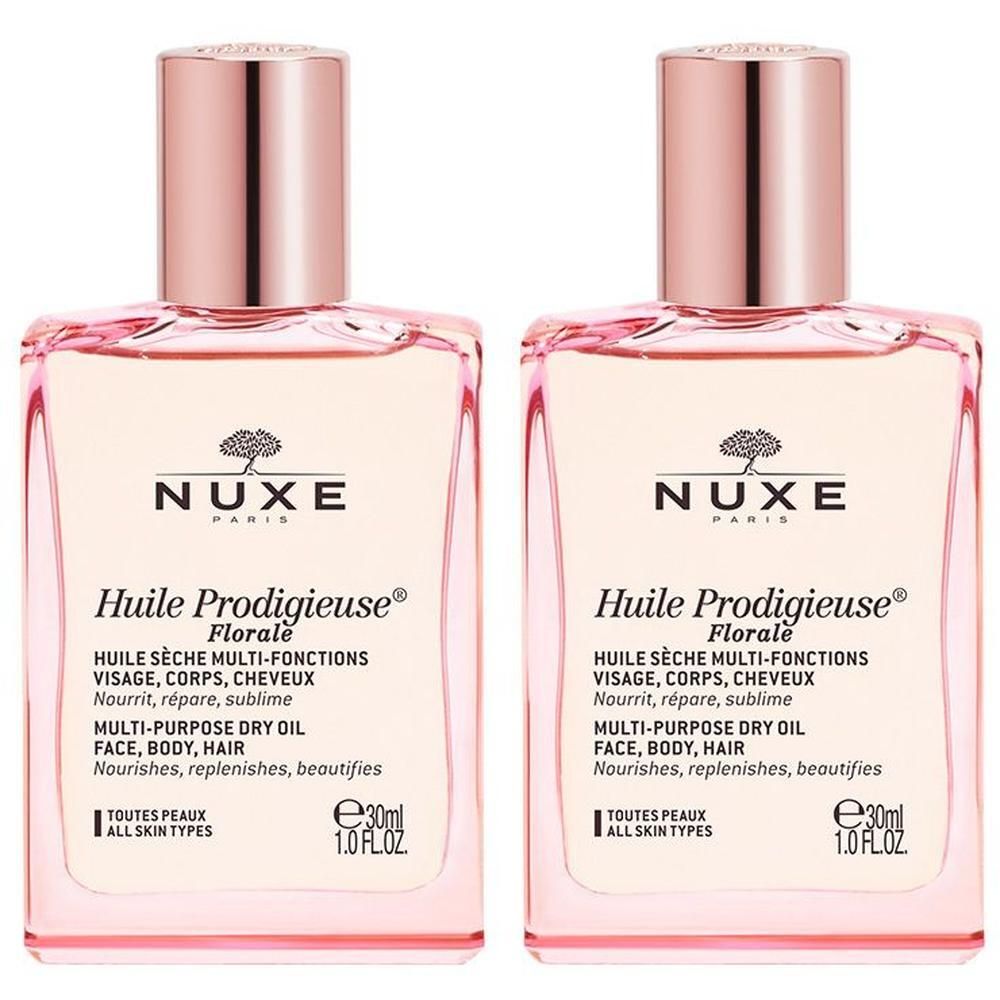 Zwei Flakons NUXE Huile Prodigieuse Florale. Quadratische Glasflaschen mit rosafarbenem Inhalt und roségoldfarbenen Verschlüssen. Text: NUXE, Huile Prodigieuse Florale.