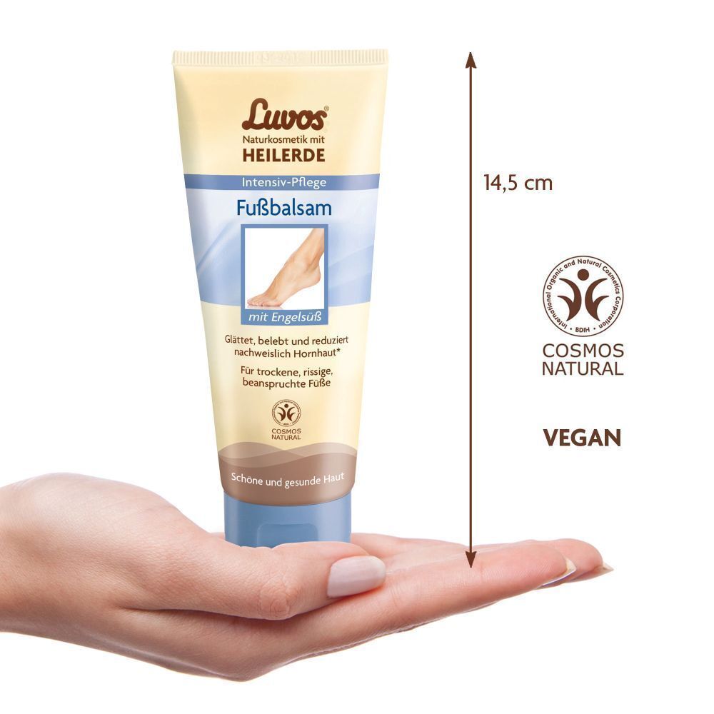 Hand hält eine Tube Luvos Heilerde Fußbalsam. Beige Tube mit blauem Deckel. 14,5 cm. COSMOS NATURAL, VEGAN.