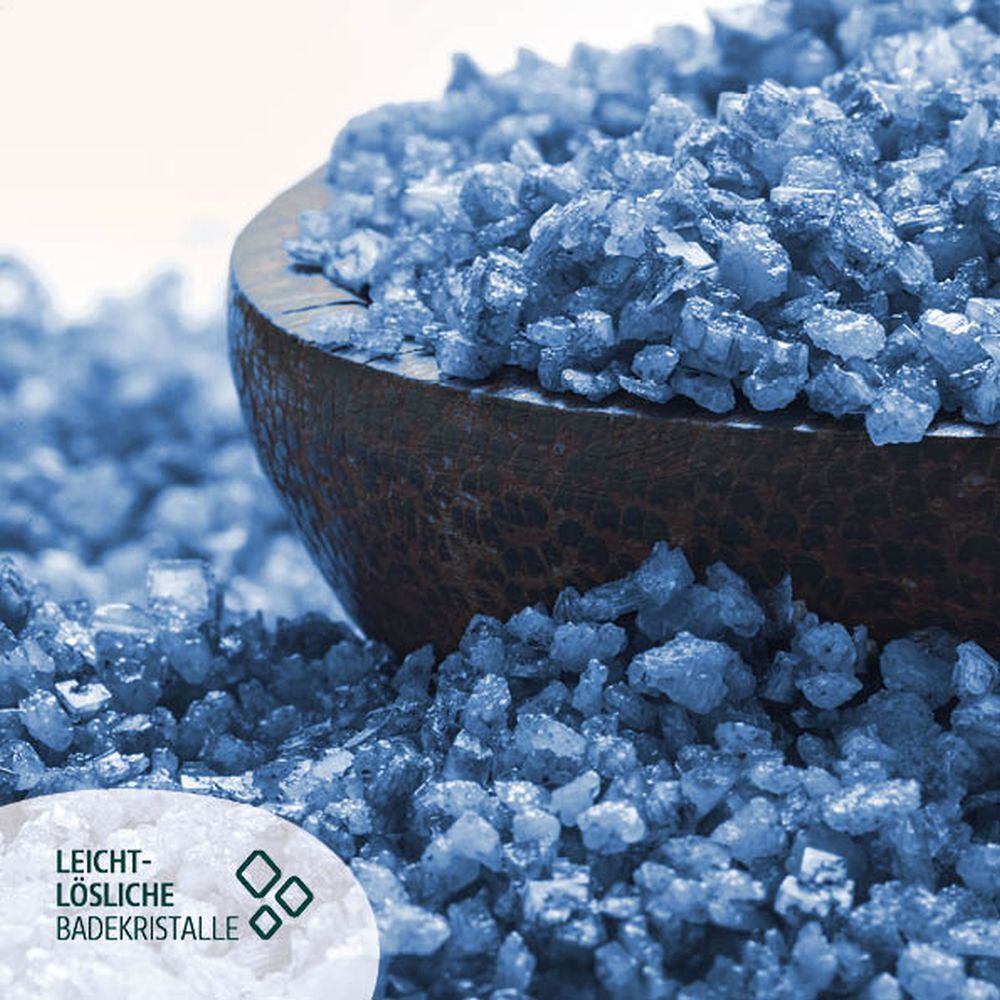 Blaue Badekristalle in einer Holzschale. Der Text 'Leicht-lösliche Badekristalle' ist sichtbar.