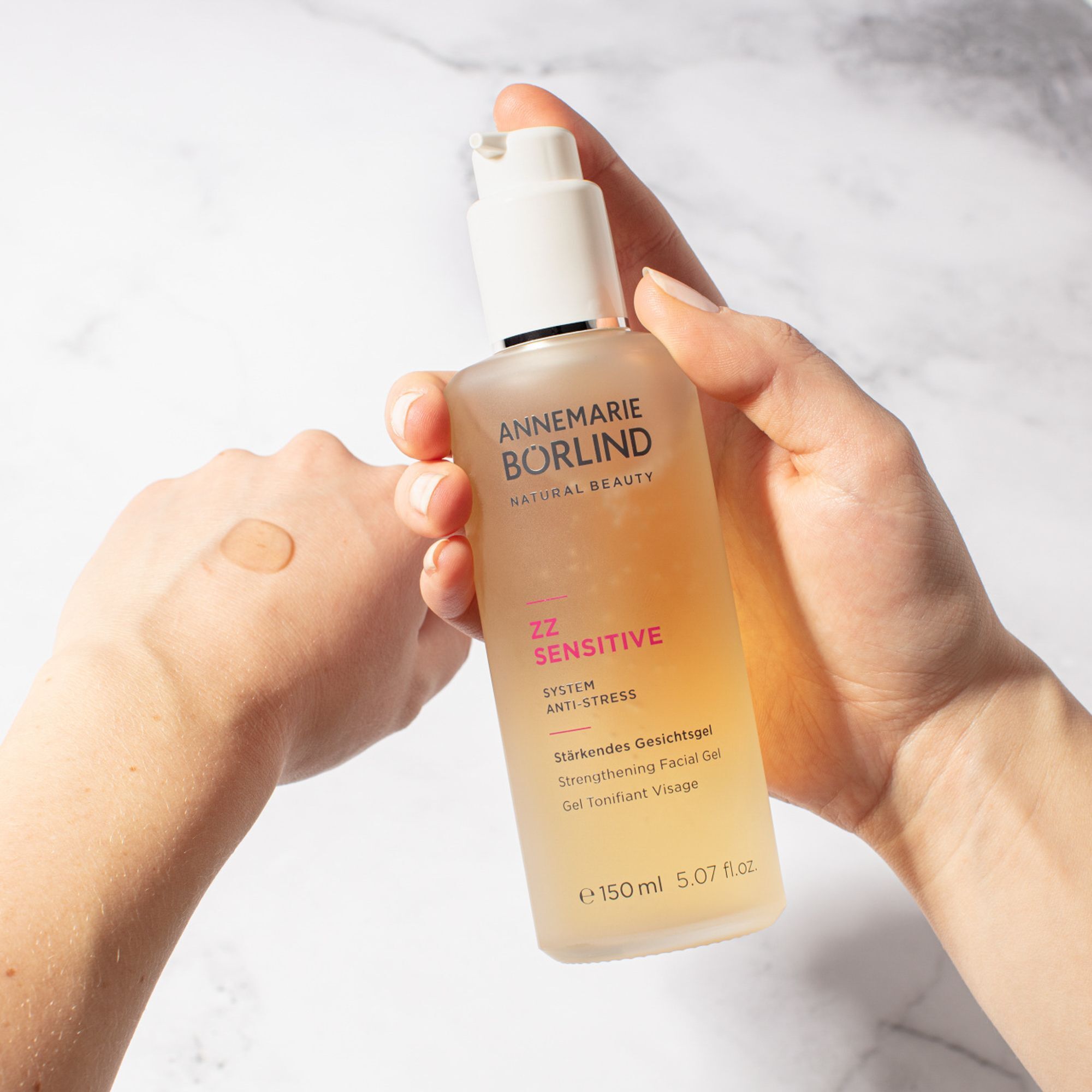 Hand hält Flasche ANNEMARIE BÖRLIND ZZ SENSITIVE Gel, ein Tropfen auf der Handfläche.