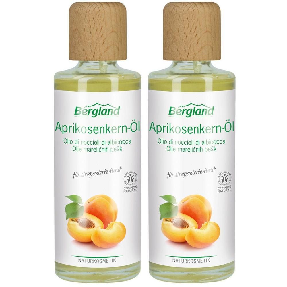 Zwei Flaschen Bergland Aprikosenkern-Öl. Glasflaschen mit Holzdeckel. Etikett mit Produktname, Abbildung von Aprikosen und dem Naturkosmetik-Siegel.