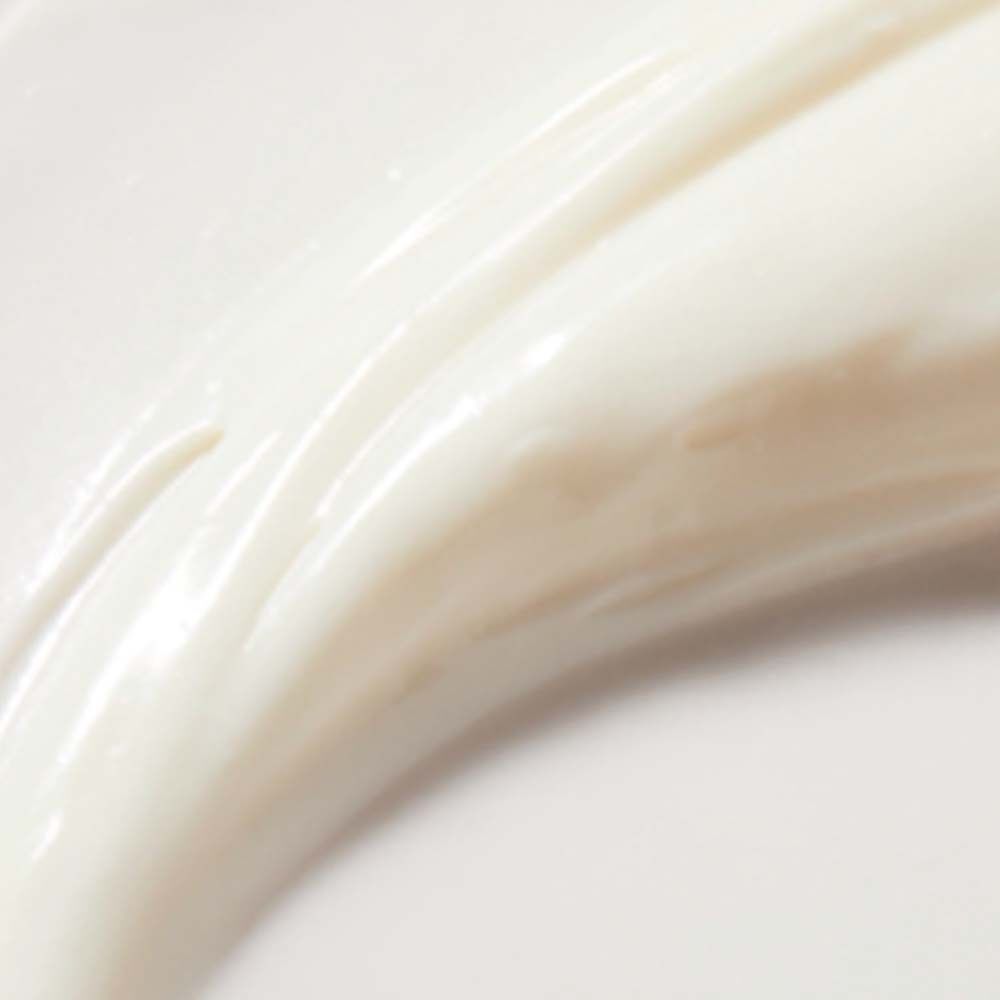 Nahaufnahme von weißer Creme. Die Creme ist glatt und glänzend. Sie hat eine wellenförmige Textur.