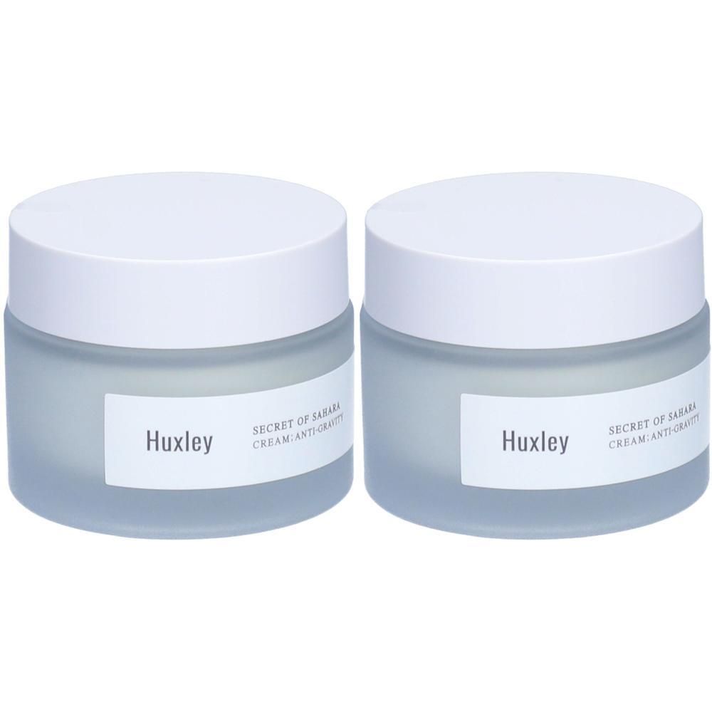 Zwei Cremetiegel mit weißen Deckeln. Auf den Etiketten steht "Huxley" und "SECRET OF SAHARA CREAM ANTI-GRAVITY".