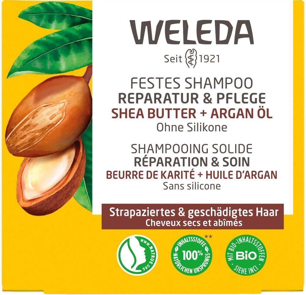 Gelbe Produktverpackung mit Text: "WELEDA", "FESTES SHAMPOO Reparatur & Pflege". Abbildung von Shea Butter und Arganöl.
